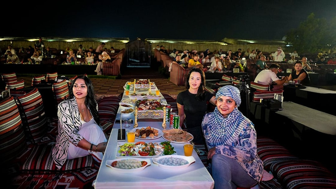 People enjoying evening live performance and dining at a desert safari experience.