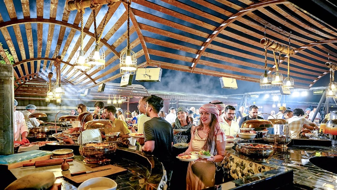 Guests enjoying buffet dinner under wooden canopy during evening desert safari.