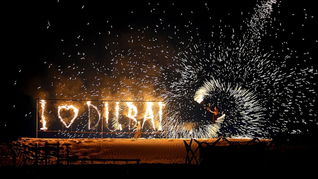 Fire performer with "I ♥ DUBAI" sign during evening desert safari.