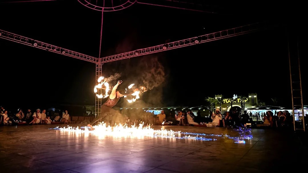 Fire performer at evening desert safari show, surrounded by audience, Dubai.