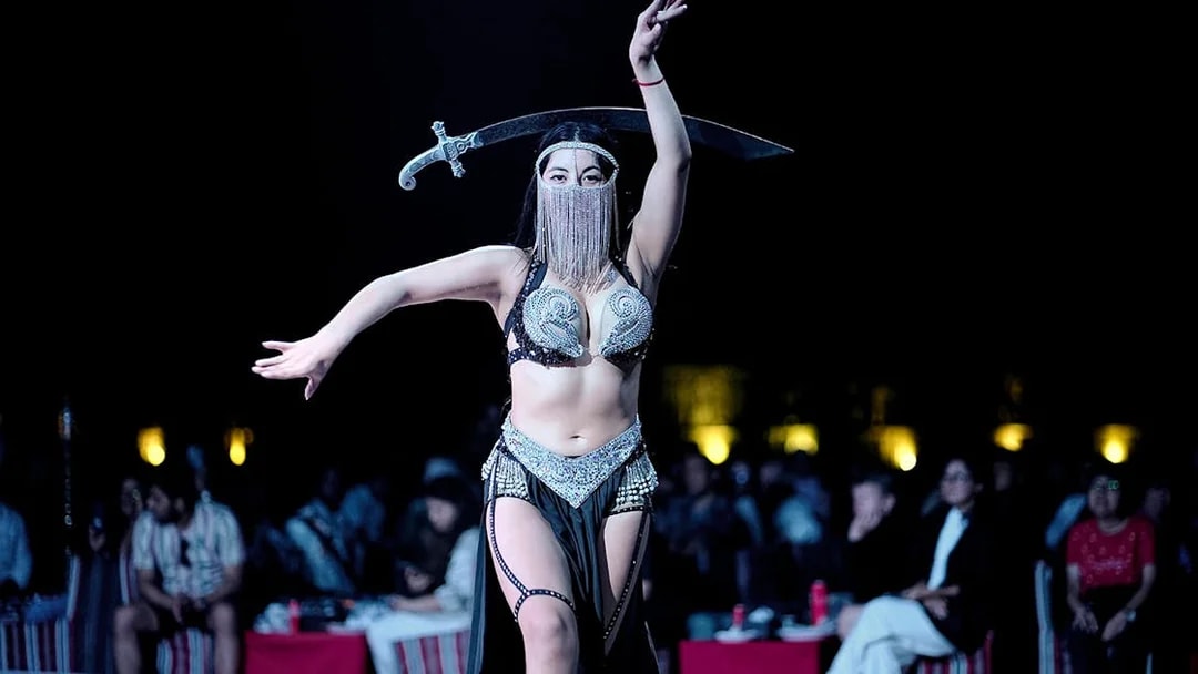 Belly dancer performing with a sword during an evening desert safari show.