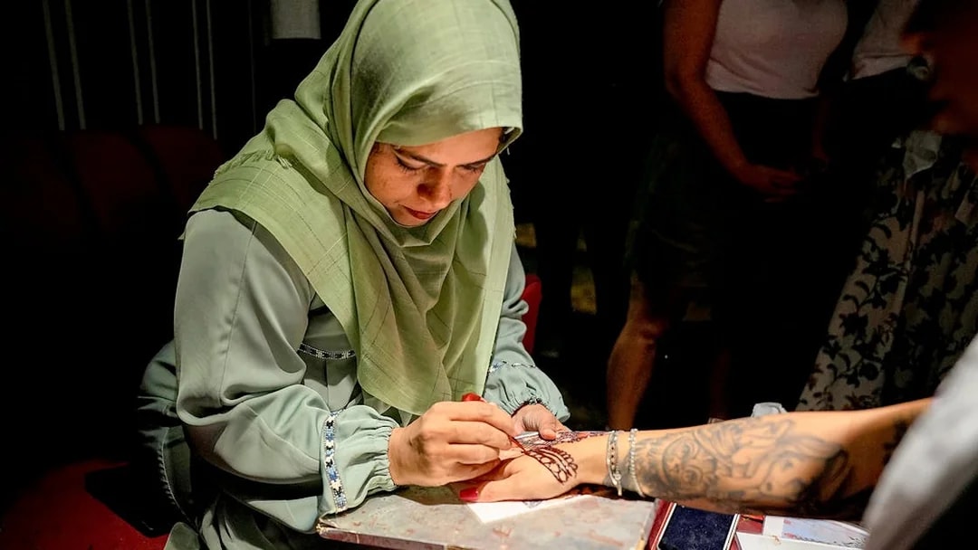 Skilled artist applying henna design on a person's hand.