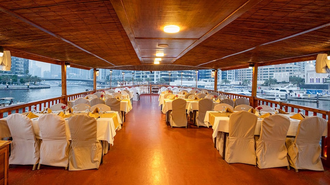 Dhow cruise dining setup with tables and chairs on Dubai Marina.