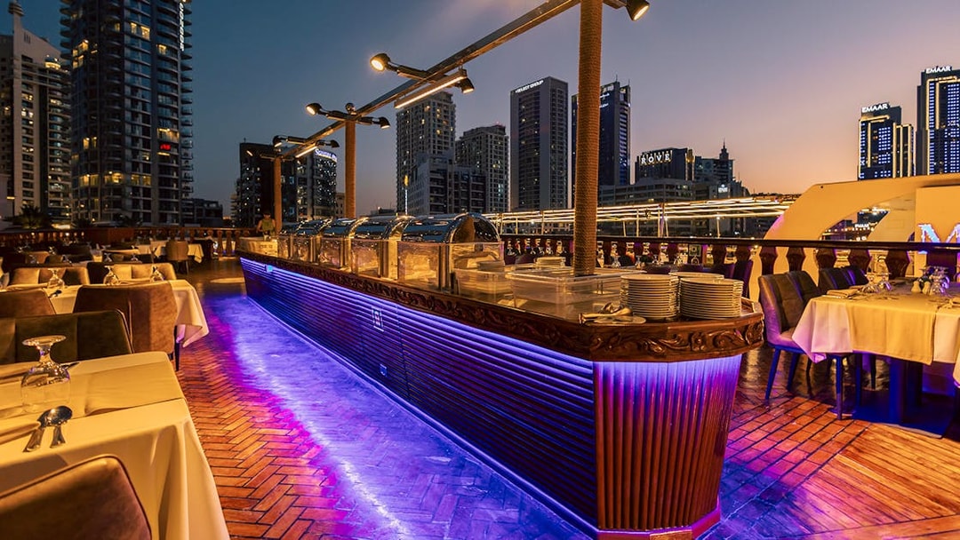 Dinner setup on Alexandra Dhow Cruise with city skyline view, Dubai Marina.