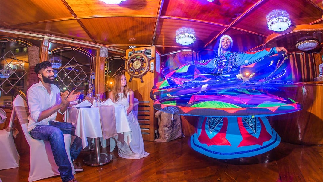 Dancers perform traditional Tanoura dance on Dubai Marina dhow cruise with guests dining.