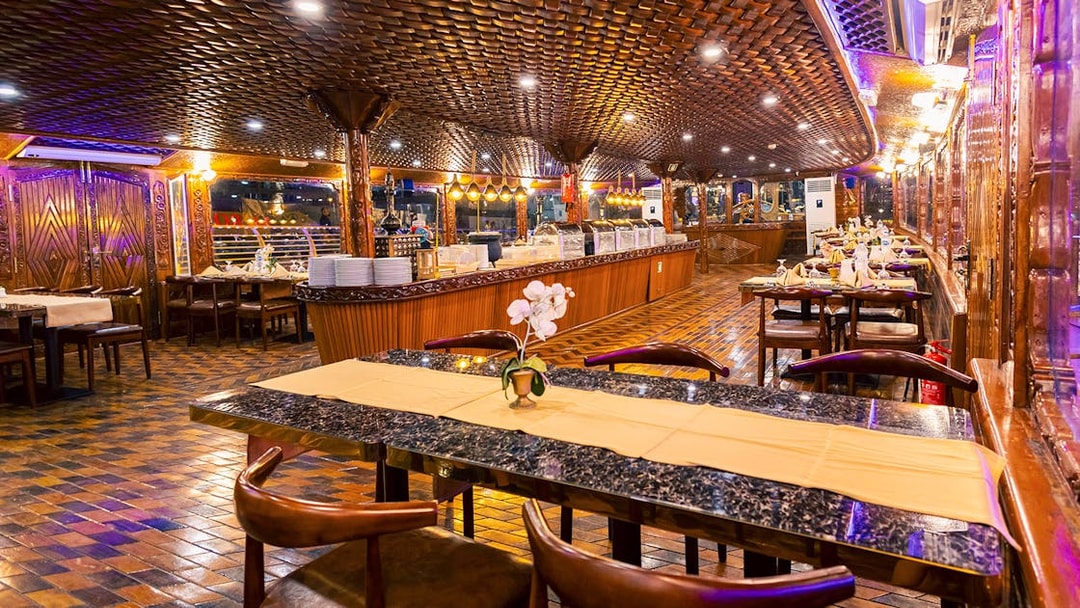 Elegant dining setup on Alexandra Dhow Cruise, Dubai Marina, with buffet and ambient lighting.