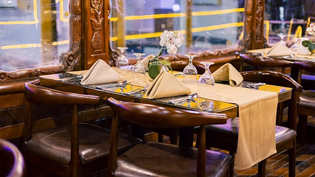 Elegant dining setup on Alexandra VIP Dhow Cruise with folded napkins and glassware.