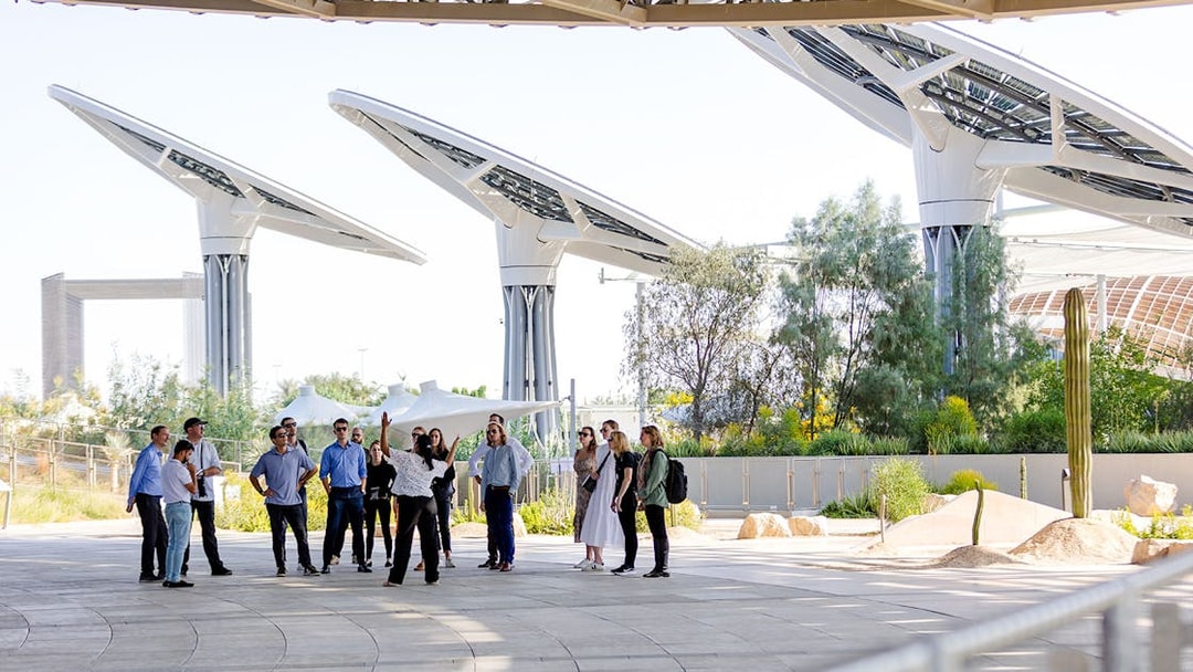 Guide leading a group tour at Expo City Dubai with futuristic structures in the background.