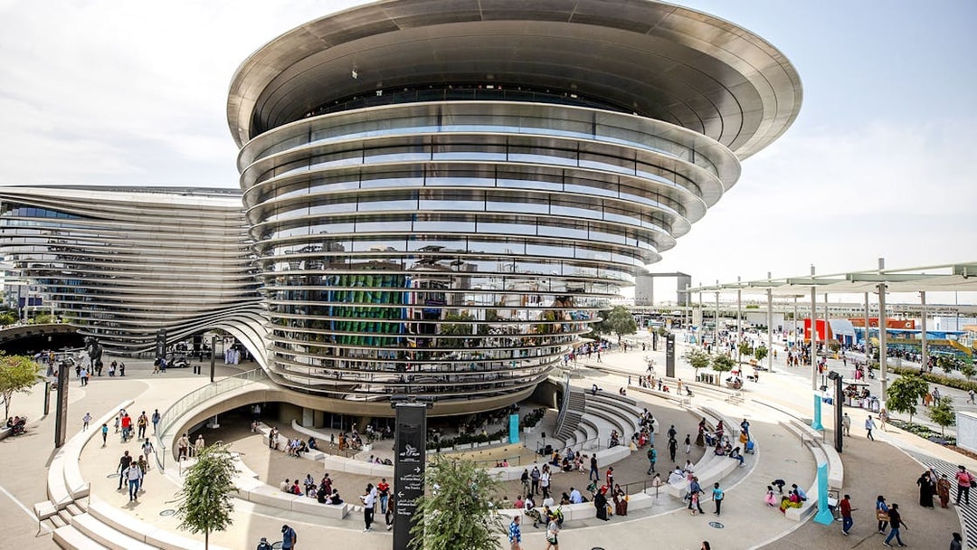 Aerial view of Expo City Dubai entrance with modern architecture and visitors.