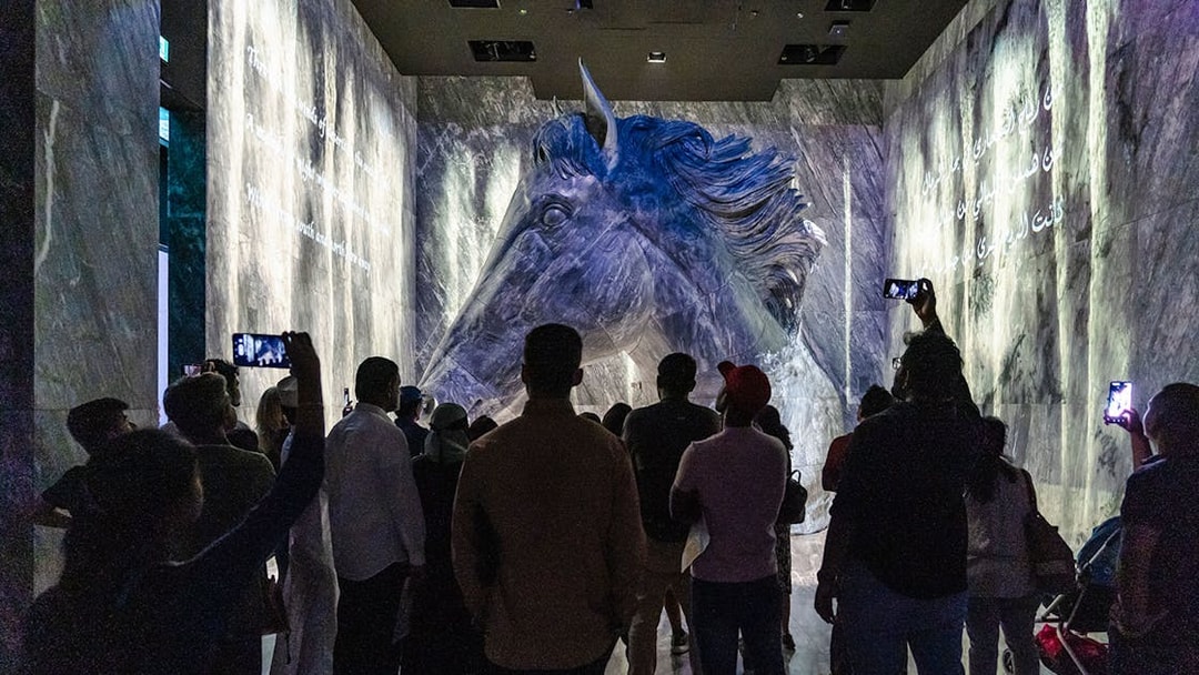 Guide interacting with tourists in front of a large horse sculpture at Expo City Dubai.
