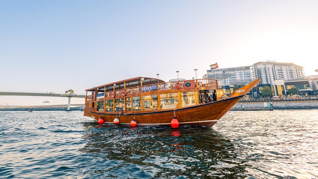 Dhow boat cruising near Dubai Marina during sunset, part of the Alexandra VIP Dhow Cruise experience.