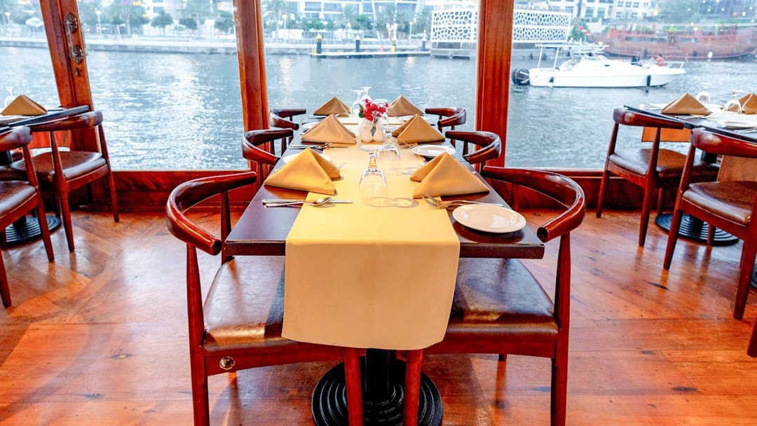 Elegant dining setup on a dhow cruise with waterfront view, part of the Sunset Alexandra VIP experience.