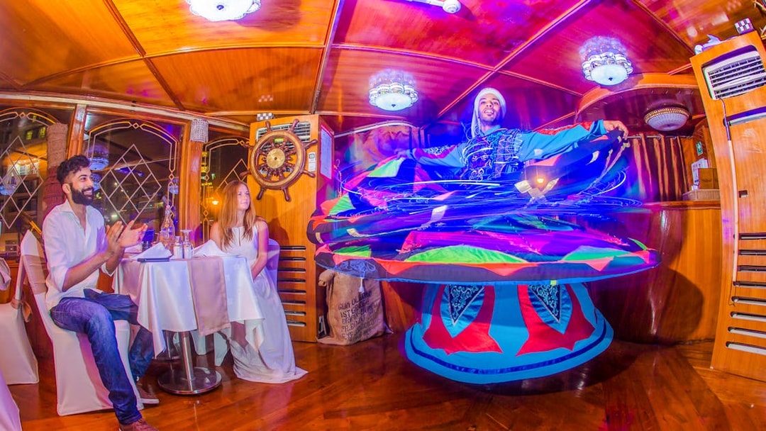 Tanoura dancer performing on Alexandra VIP Dhow Cruise with guests watching.