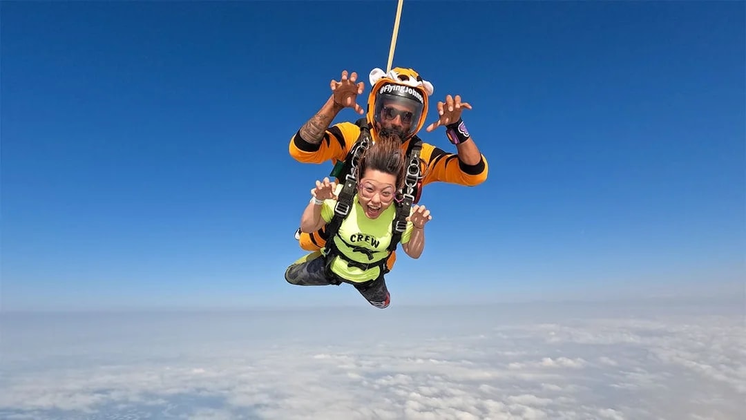 Tandem skydivers over Dubai's Palm Drop Zone with clear blue sky.