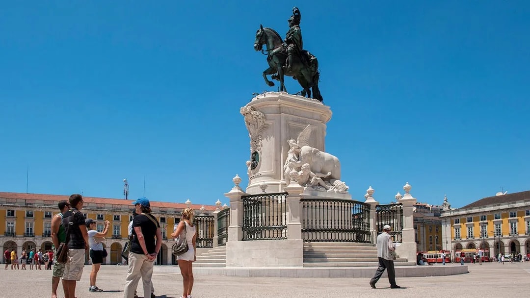 Tourists at Praça do Comércio in Lisbon with equestrian statue of King José I.