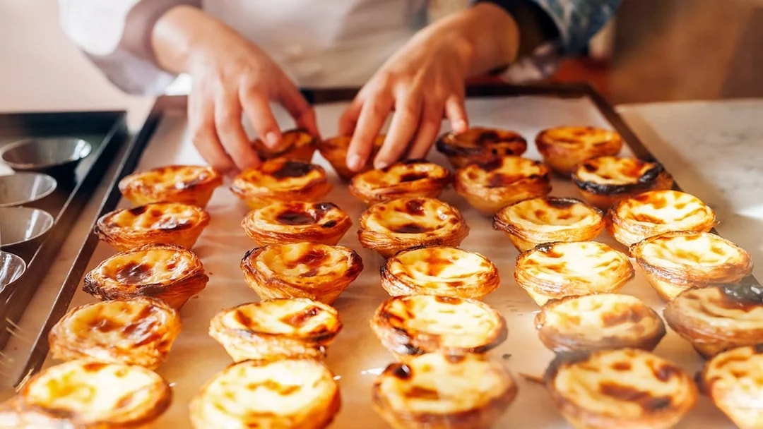 Pastéis de Nata being arranged on a tray during Lisbon & Belém Small Group Tour.