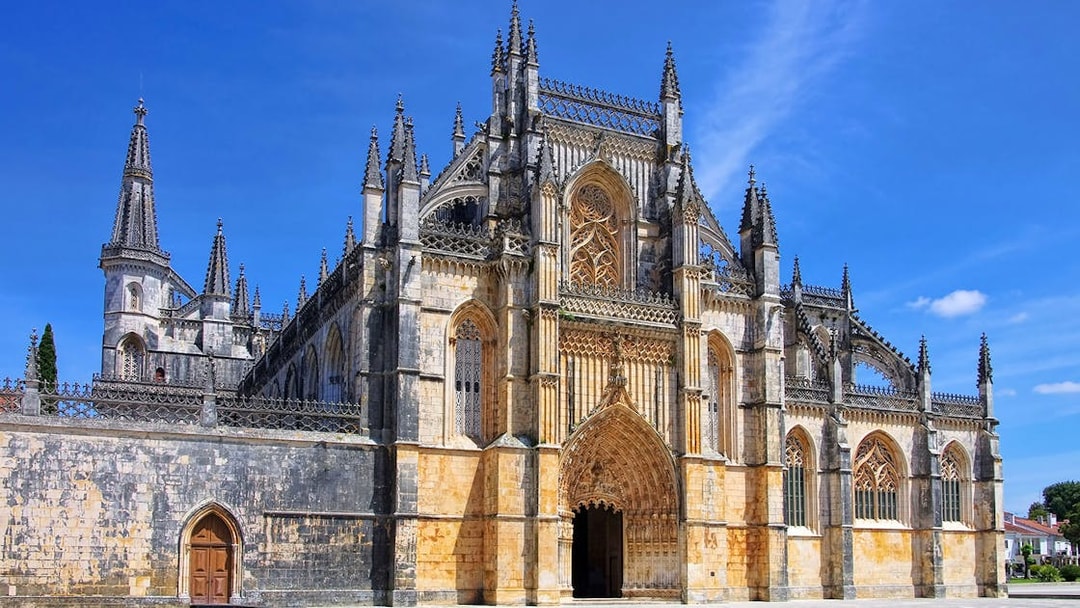 Batalha Monastery's intricate Gothic facade under a clear blue sky, Lisbon.