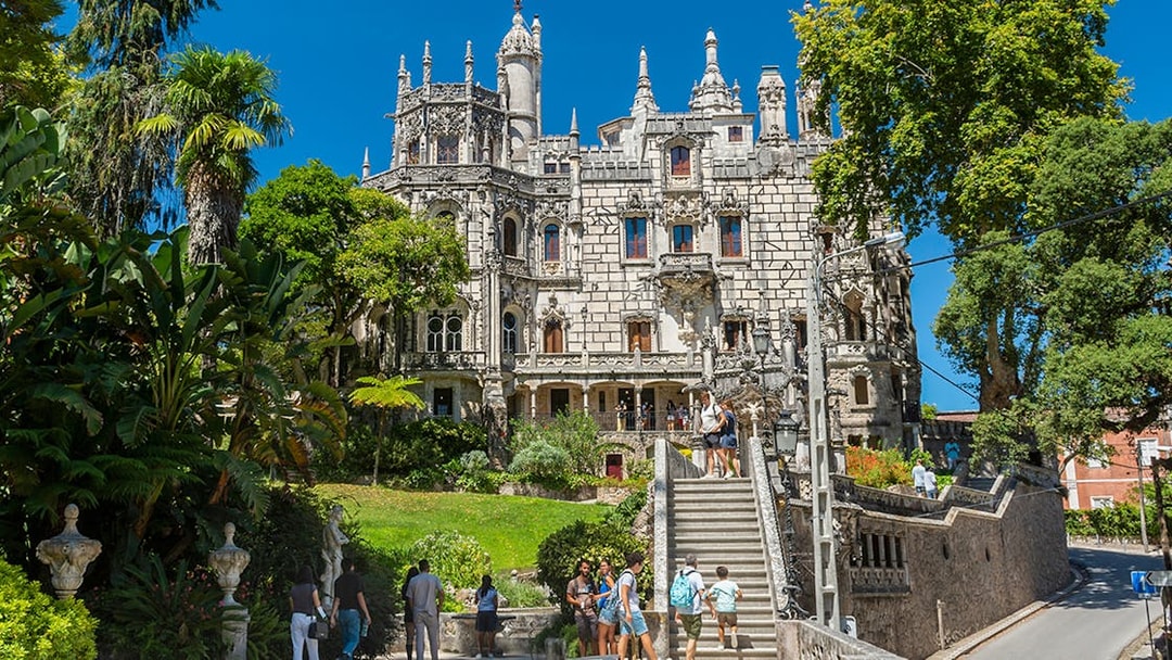 Visitors exploring gardens and architecture of Quinta da Regaleira, Sintra, Portugal.