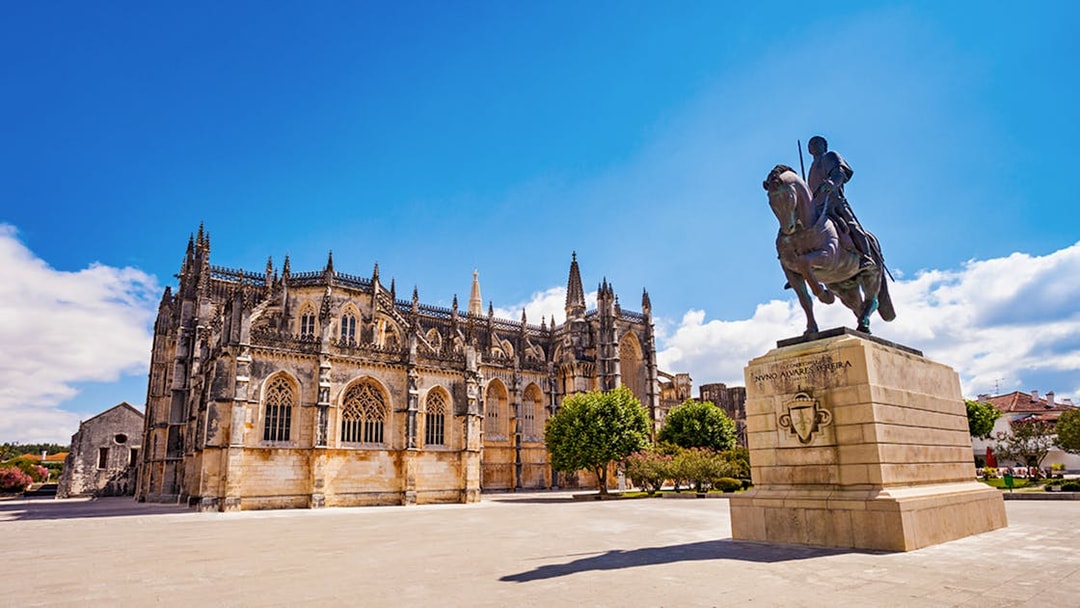 Batalha Monastery and equestrian statue in Batalha, Portugal, under a clear blue sky.