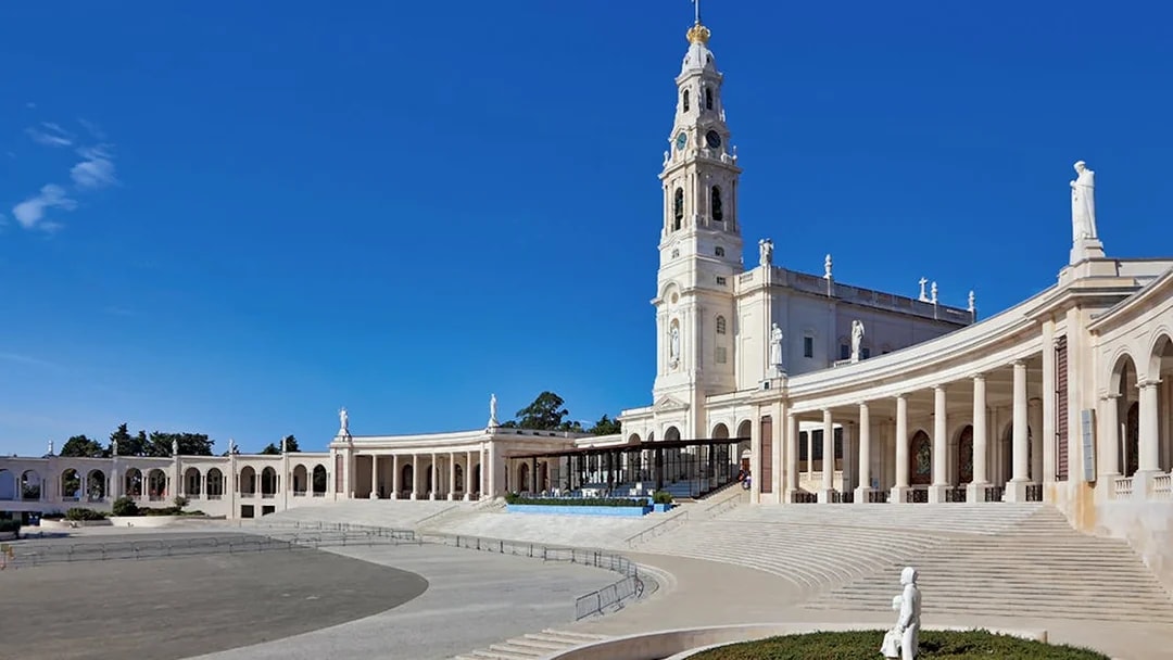 Sanctuary of Fátima with colonnade and basilica under clear blue sky.