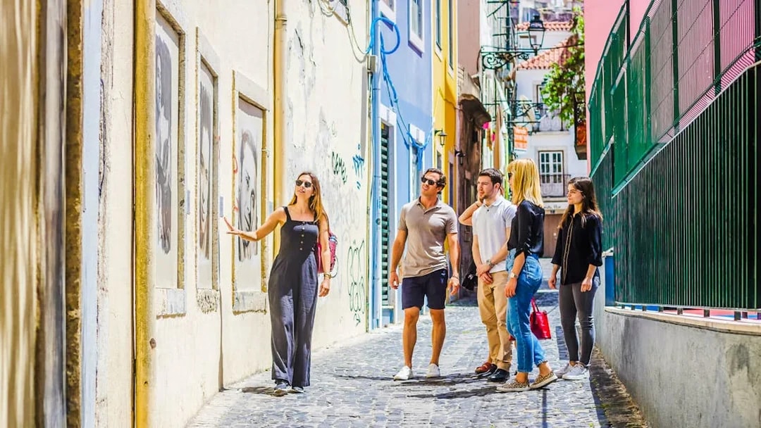 Tour group with guide exploring colorful street in Lisbon.