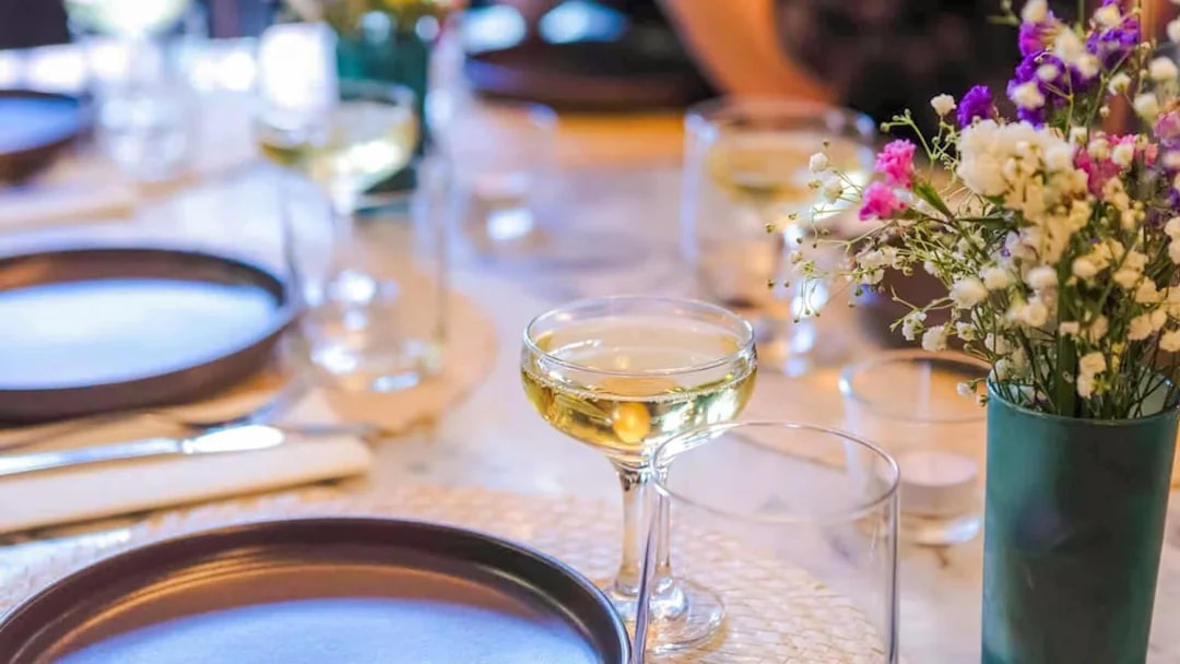 Champagne glass on a table with plates and flowers, Lisbon food tour.