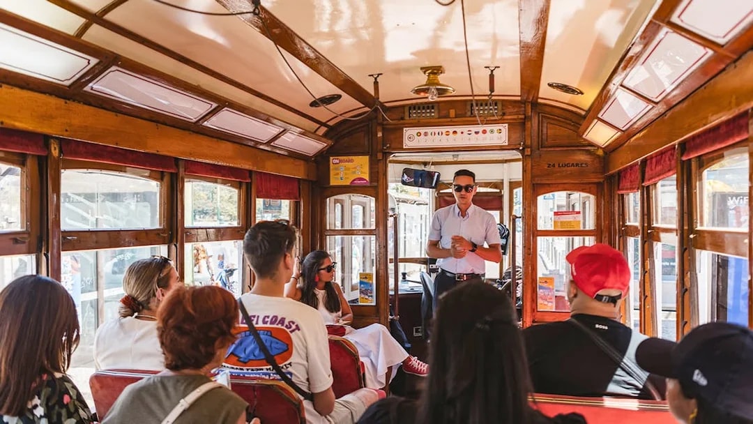 Tour guide speaking to passengers on a Lisbon tram during a hop-on hop-off tour.