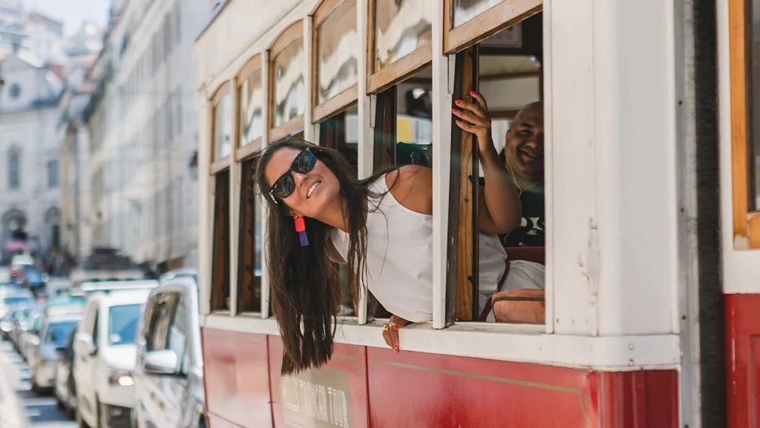 Passenger leaning out of Lisbon tram window on a city street.