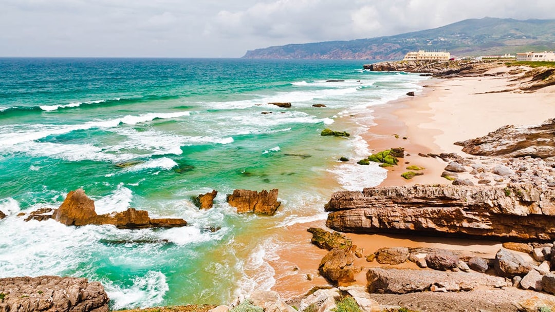 Coastal view of Cabo da Roca with rocky cliffs and turquoise waves near Lisbon.