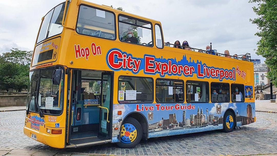 Open-top City Explorer Liverpool tour bus on cobblestone street.