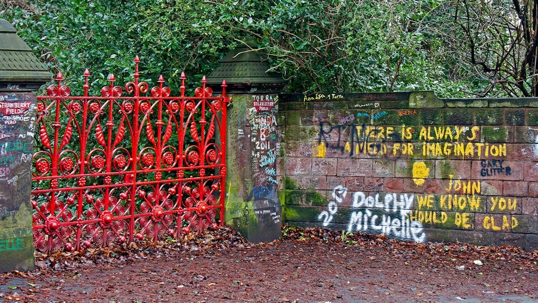 Strawberry Field Gates in Liverpool with graffiti-covered brick wall.