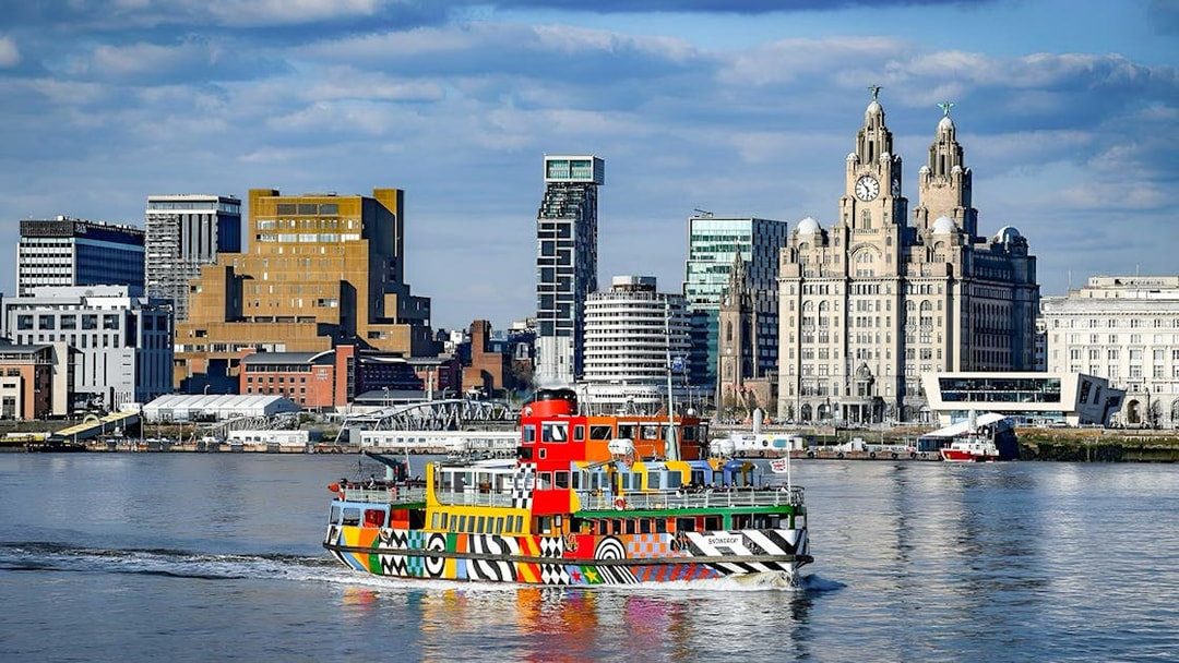 Colorful ferry on River Mersey with Liverpool skyline in the background.