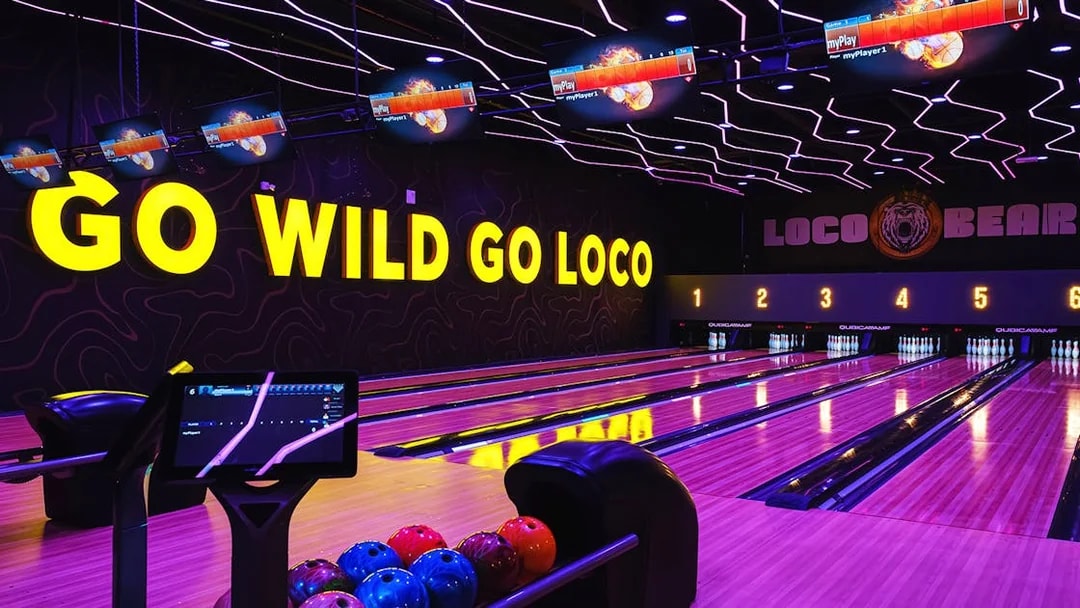 Bowling lanes at Loco Bear entertainment hub with neon "Go Wild Go Loco" sign.