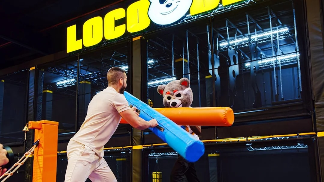 Man and person in bear costume jousting at Loco Bear entertainment hub.