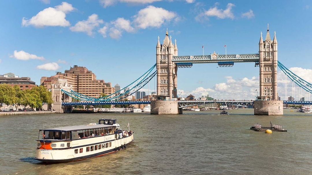 River cruise boat near Tower Bridge, London, on a sunny day.