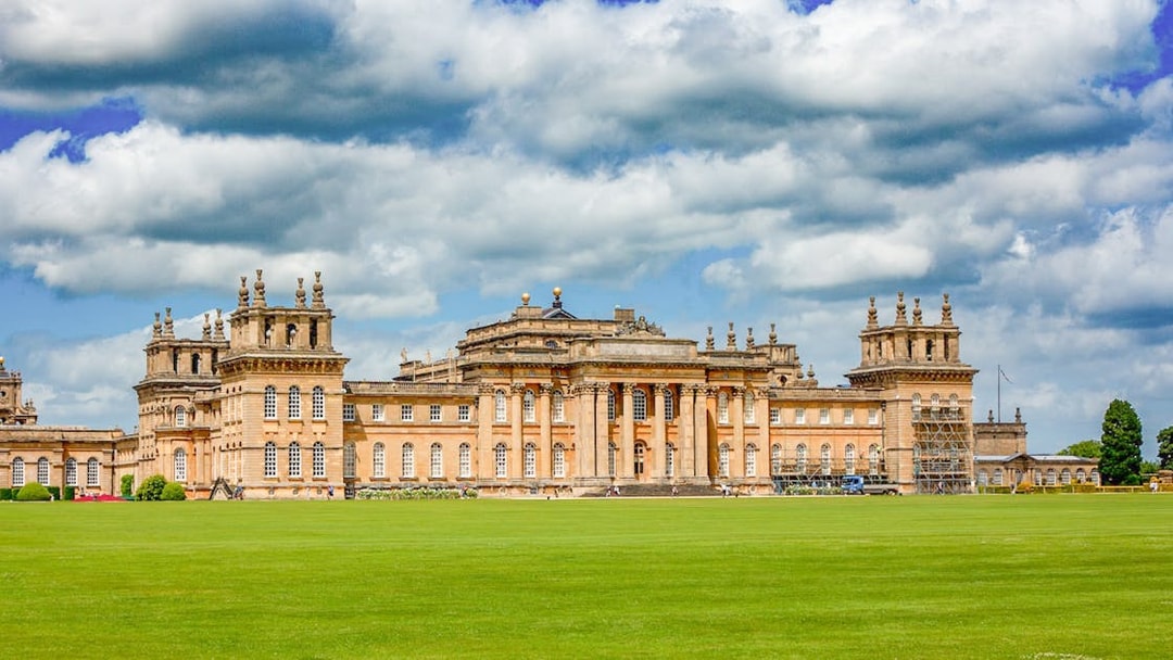 Blenheim Palace exterior with expansive lawn under a cloudy sky.