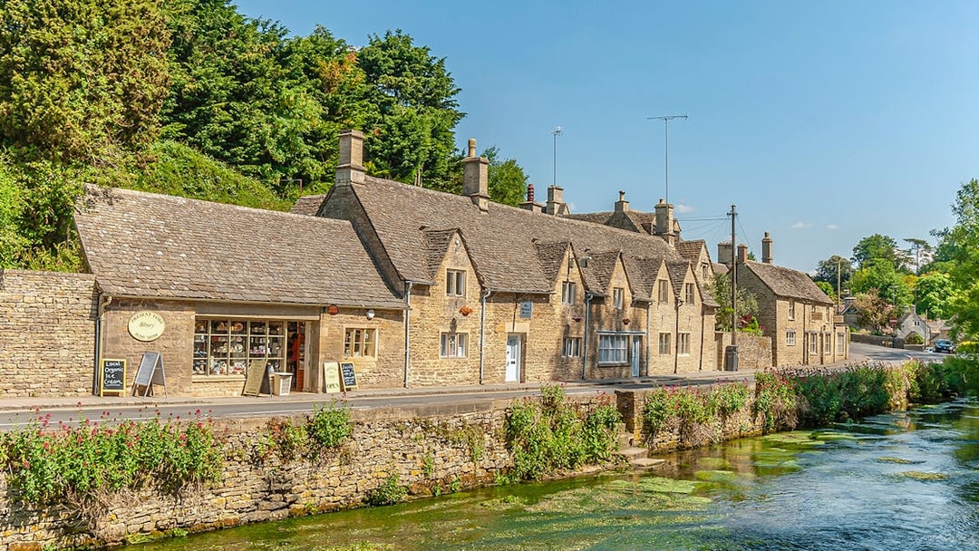 Cotswolds village street with stone cottages and a stream, part of Blenheim Palace and Downton Abbey tour.