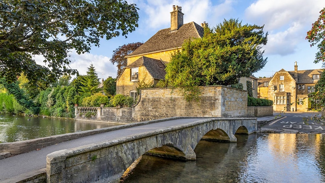 Stone bridge and historic house in a Cotswolds village, part of Blenheim Palace and Downton Abbey tour.