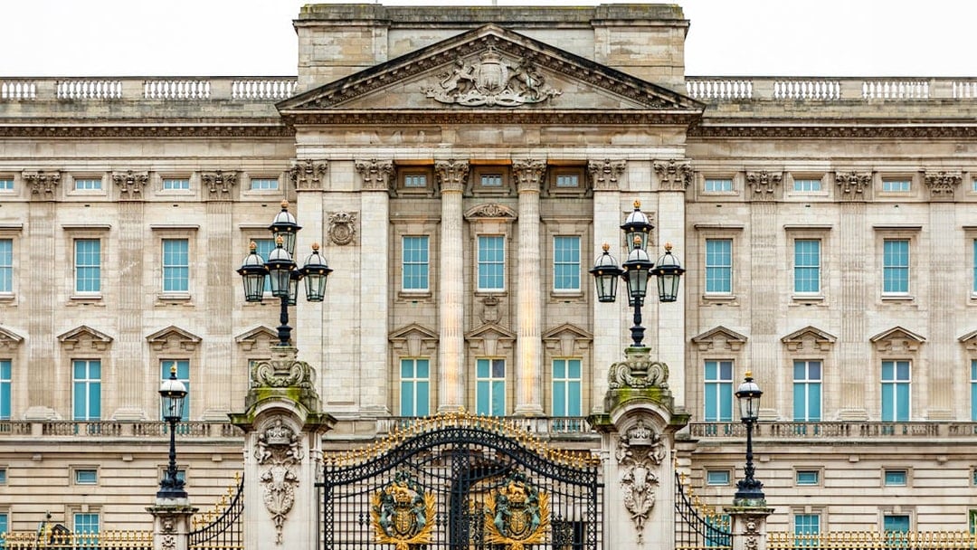 Buckingham Palace facade with ornate gates and lampposts, London.