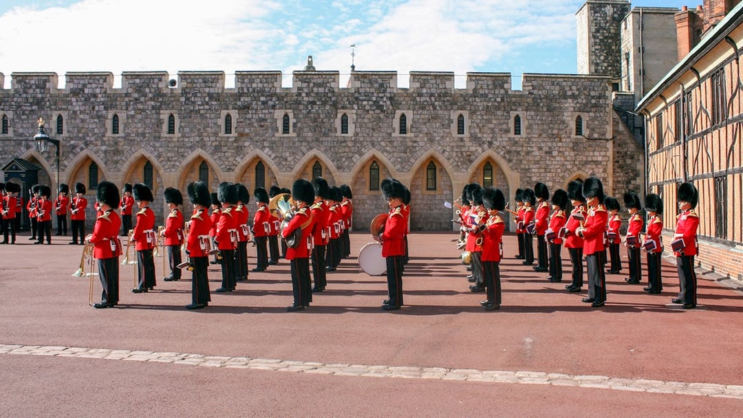 Guards in red uniforms and bearskin hats in formation at Windsor Castle.