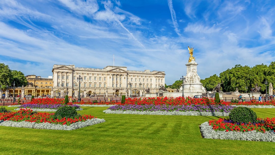 Buckingham Palace with Victoria Memorial and vibrant flower gardens in London.