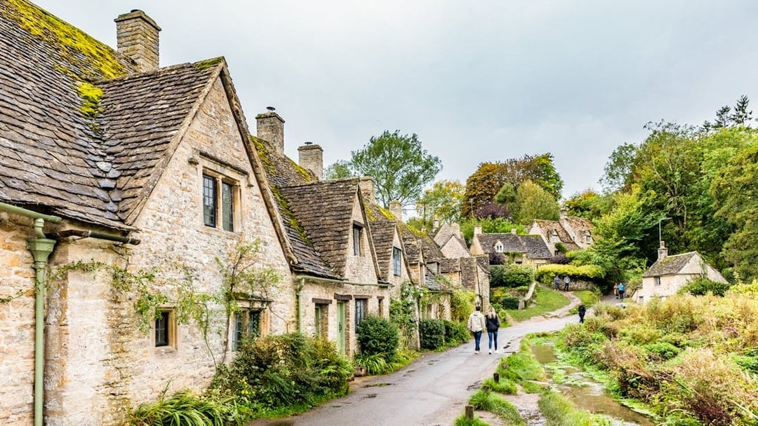 Cotswolds village path with stone cottages and greenery, part of London to Broadway Tower tour.