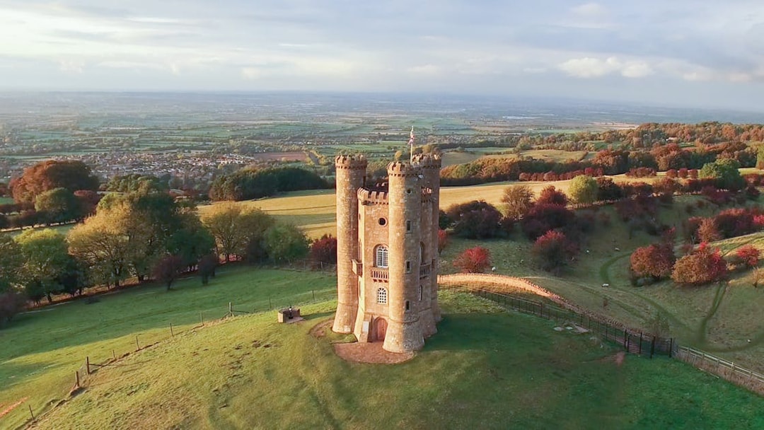 Broadway Tower in the Cotswolds countryside, England, surrounded by rolling hills.