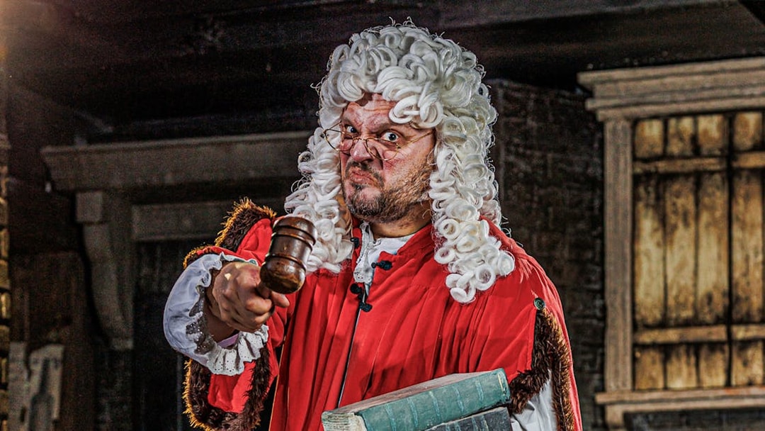 Judge in period costume holding gavel at London Dungeon attraction.