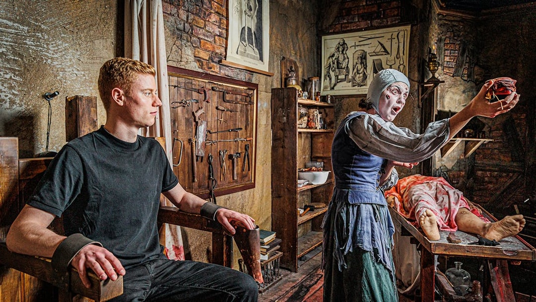 Man in a torture chamber with medieval tools at London Dungeon.