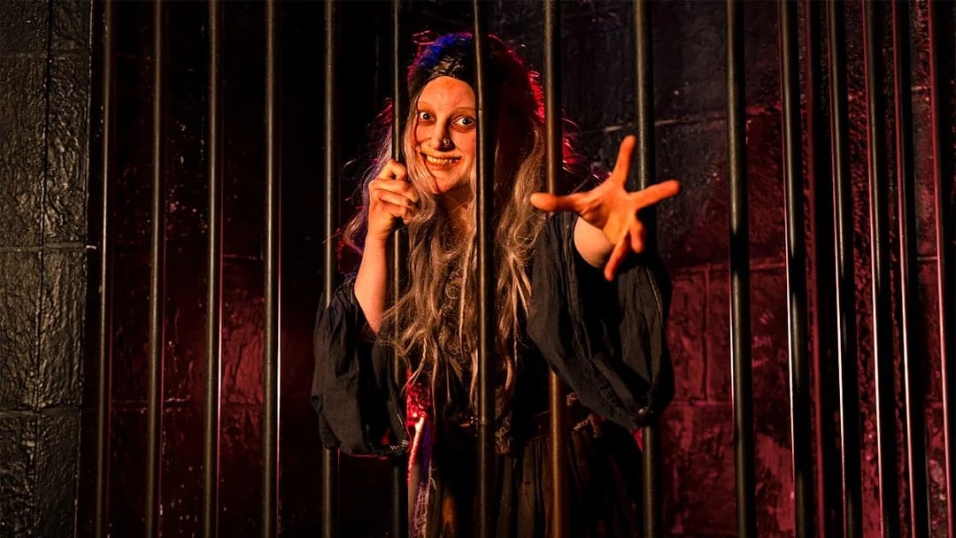 Witch role-playing behind bars at London Dungeon.