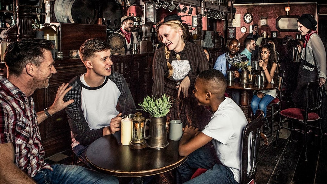 Guests enjoying drinks at a themed tavern as part of the London Dungeon premium package.