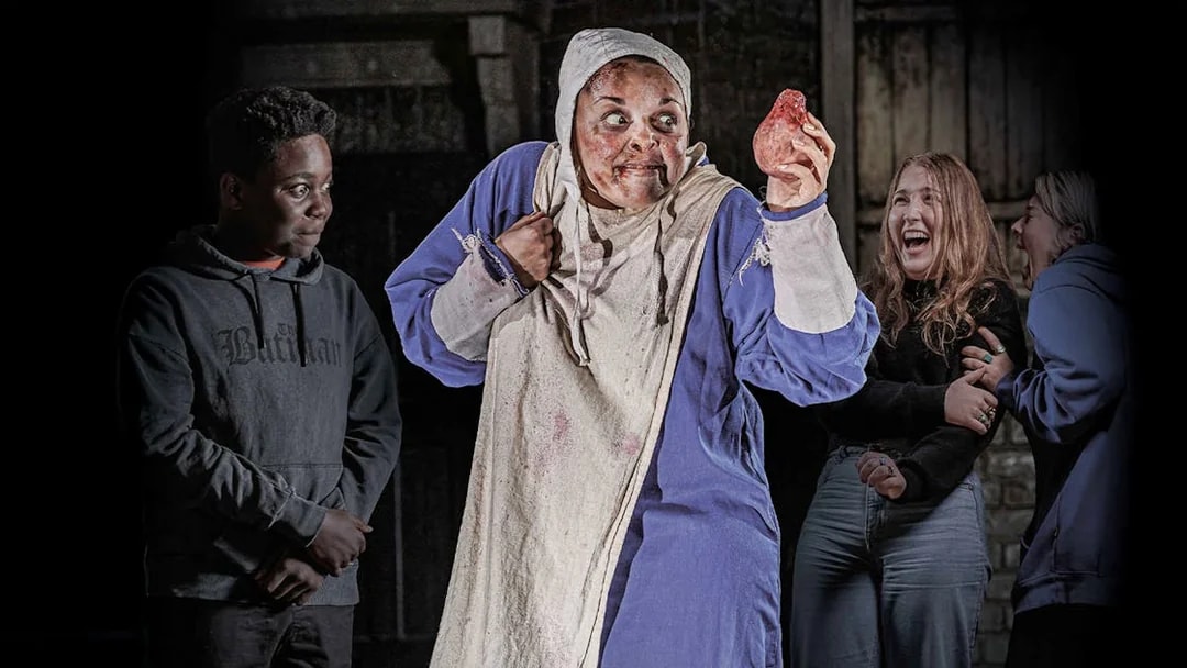 Performer in costume holding a prop heart at London Dungeon VIP experience.