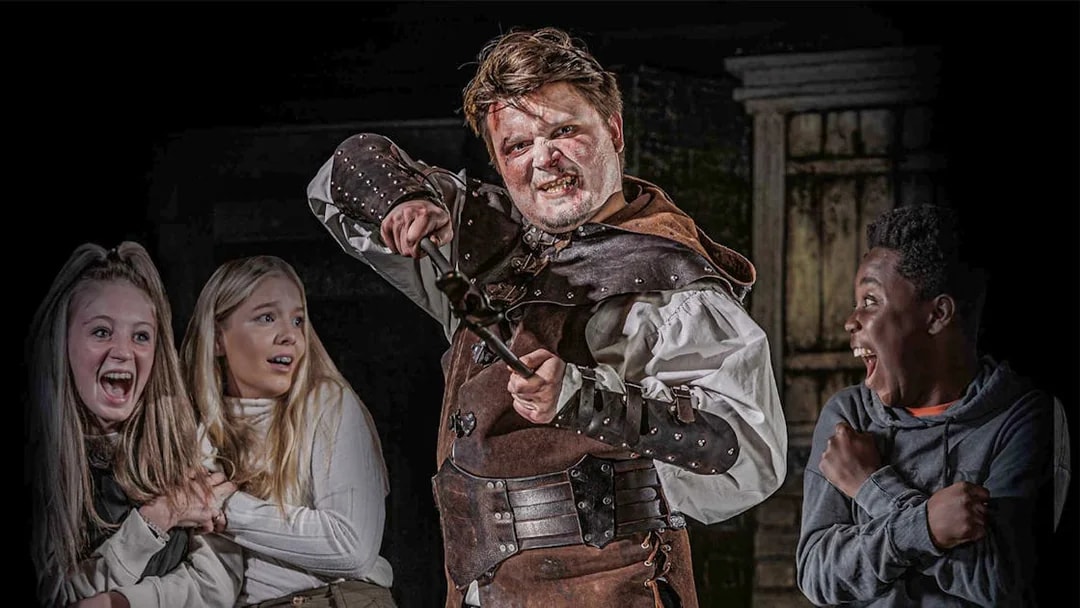 Actor in medieval costume scaring visitors at London Dungeon VIP experience.