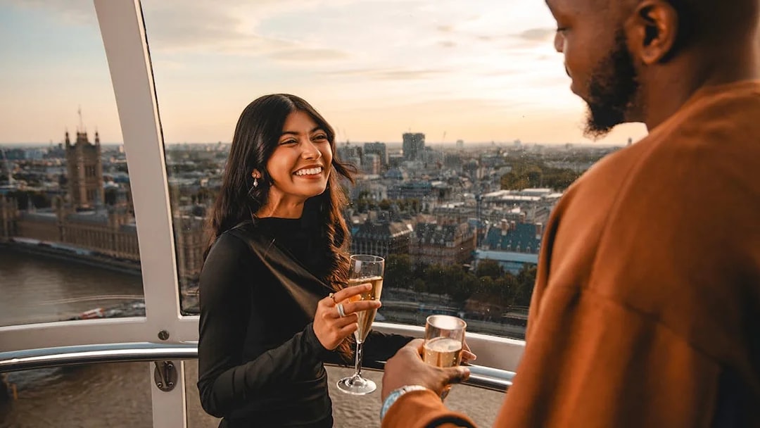 Couple enjoying champagne on the London Eye with cityscape view.